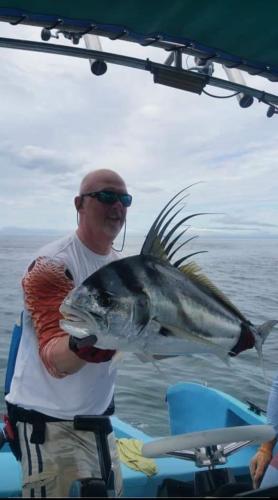 a man on a boat holding a large fish at Hostel Hook and Cook in Drake
