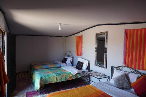 a bedroom with two beds and a table and a mirror at Mhamid Tours in Mhamid