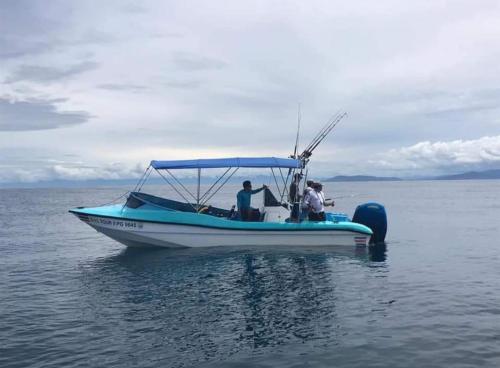 three people on a blue and white boat in the water at Hostel Hook and Cook in Drake