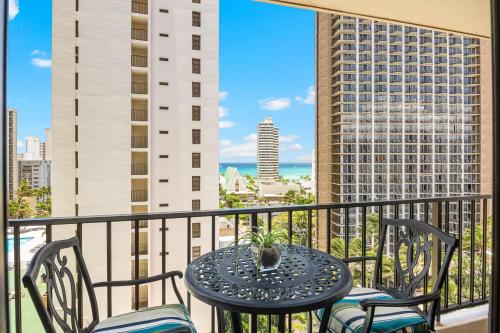 a table and chairs on a balcony with a view of the city at Waikiki Beach Ocean View King Bed & Free Parking in Honolulu