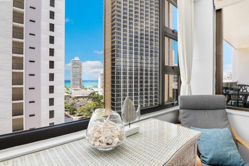 a living room with a table and a chair and windows at Waikiki Beach Ocean View King Bed & Free Parking in Honolulu
