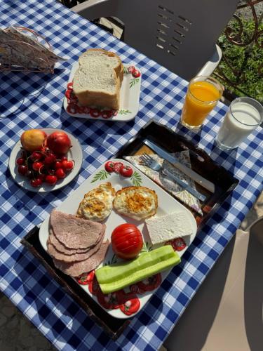 a table with a blue and white checked table cloth with food at Lake Bliss Cabins in Shkodër