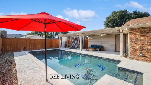 a swimming pool with a red umbrella and a house at Spectacular 4BR 2,5BA Holiday Home with Pool and Grill in Carrollton