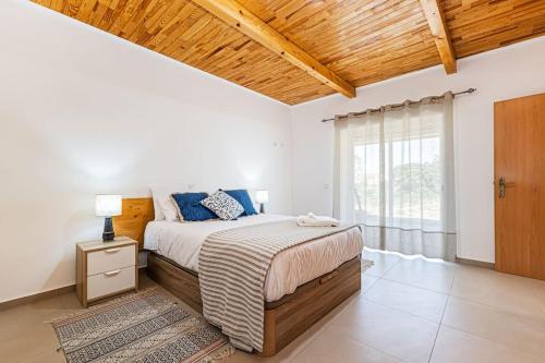 a bedroom with a large bed with a wooden ceiling at Salicos House - Lagoa - Benagil in Lagoa