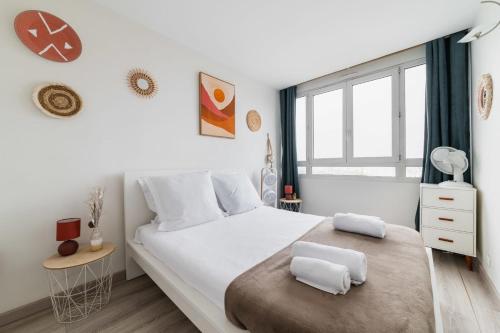 a white bedroom with a large bed and a window at Appartement Versailles Eiffel in Vanves