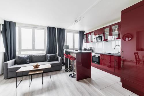 a living room with a couch and a kitchen with red cabinets at Appartement Versailles Eiffel in Vanves