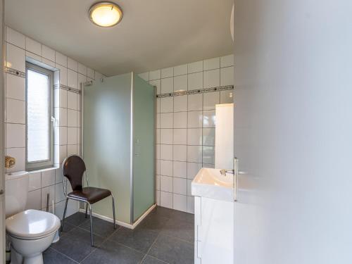 a bathroom with a toilet and a chair in it at De Kievelder in Peer