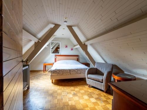 a attic bedroom with a bed and a chair at De Kievelder in Peer