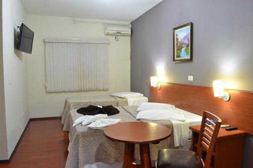 a room with two beds and a table and a table at Hotel Rafeli in Boituva