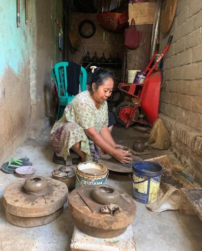a woman is making pottery in a room at Alfarizi homestay in Tetebatu