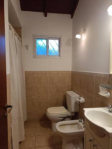 a bathroom with a toilet and a sink and a window at Casa quinta espaciosa in Ingeniero Maschwitz