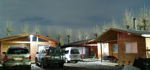 dos coches estacionados frente a una cabaña de madera en Cabañas EcoSur - Chile, en Curacautín