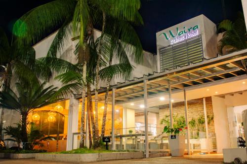 a building with palm trees in front of it at Waira Suites in Leticia