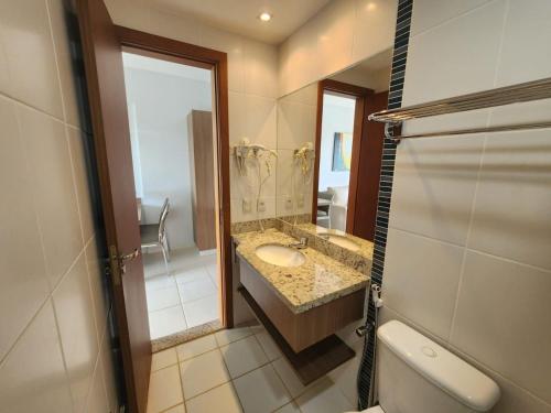 a bathroom with a sink and a large mirror at Apartamentos em Rio Quente com maravilhosa área de lazer e excelente localização in Rio Quente
