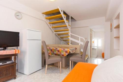 a kitchen and dining room with a table and a spiral staircase at Apartments by the sea Baska, Krk - 19519 in Baška