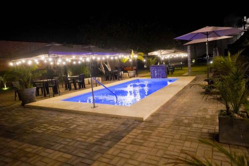 a swimming pool at night with tables and umbrellas at Silver Inn Hotel in Cerro Azul