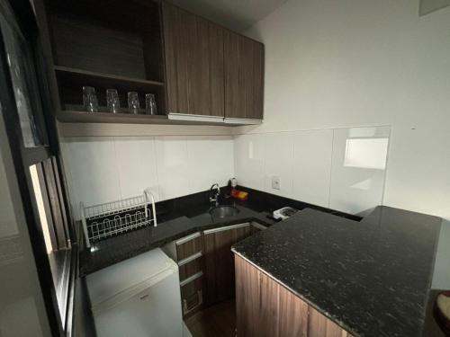 a kitchen with a black counter top and wooden cabinets at 1810 - Flat para temporada em Goiania-proximo ao Parque Areião in Goiânia