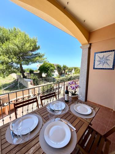a wooden deck with two tables with plates on it at Il tramonto tra Alghero e Stintino in Palmadula