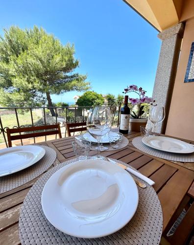 a table with white plates and wine glasses on it at Il tramonto tra Alghero e Stintino in Palmadula