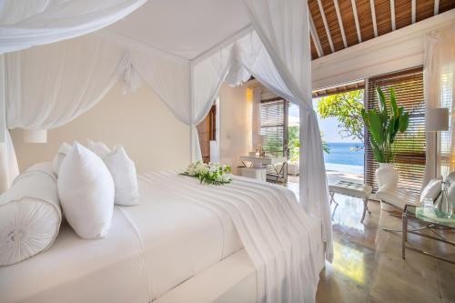 Dormitorio blanco con cama blanca y almohadas blancas en Shunyata Villas Bali, en Seraya