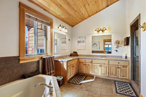 un baño con bañera y lavabo en Hint of Heaven by KABINO HotTub Air Hockey Firepit Fishing Trails Yellowstone Free WiFi, en Island Park