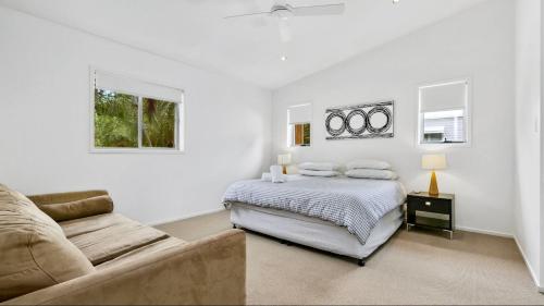 um quarto branco com uma cama e um sofá em 9 Depper St - Upper Level Only em Sunshine Beach