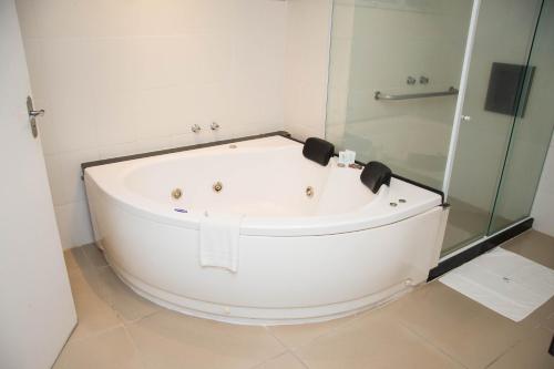 a white bath tub in a bathroom with a shower at Athos Hotel in Teresópolis