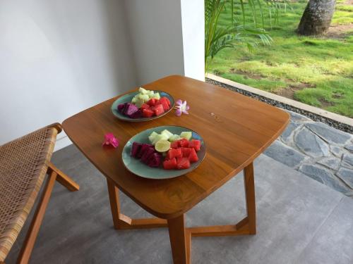 dos platos de fruta sentados en una mesa de madera en Rumah Markisa Batukaras en Batukaras