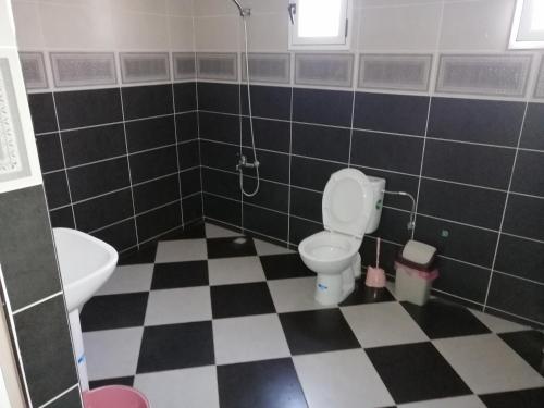 a bathroom with a toilet and a checkered floor at Bokidan appartement in Andalouciene
