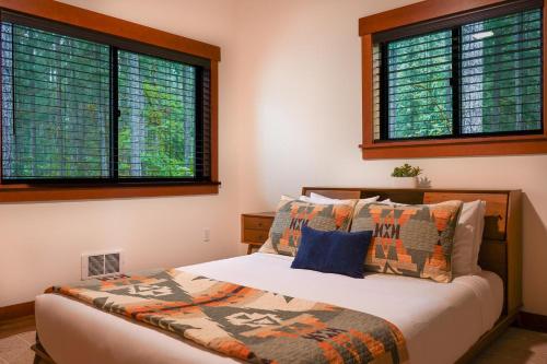 a bedroom with a bed and two windows at Elysian at Mount Baker in Glacier