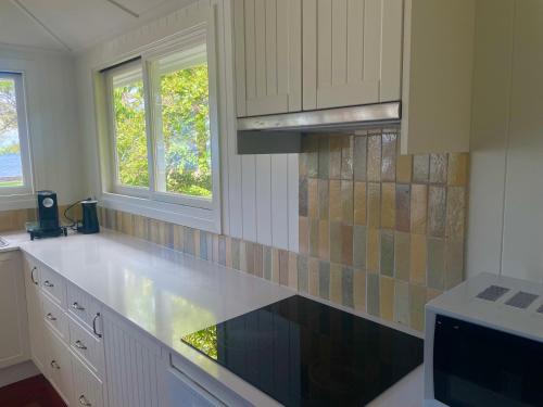 a kitchen with a white counter top and two windows at Flinders Seaside Cottage in Brighton