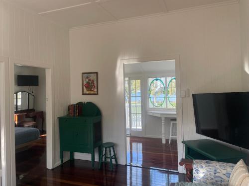 a living room with a television and a green cabinet at Flinders Seaside Cottage in Brighton