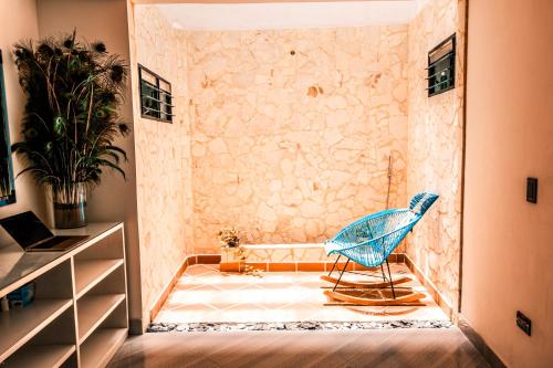 a blue chair in a room with a stone wall at Casa Finca La Nana in San Jerónimo