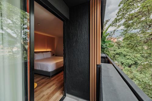 a room with a bed and a window at The Somos Central Hotel Poblado in Medellín