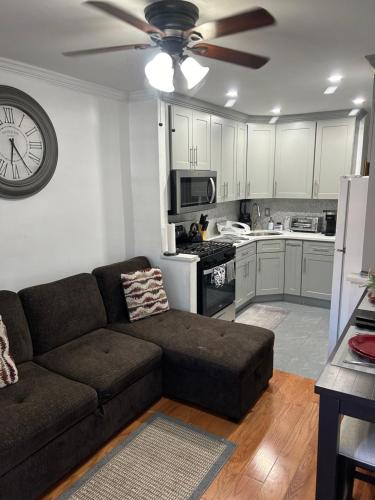 a living room with a couch and a clock on the wall at Cozy Canarsie Getaway Brooklyn NY in Brooklyn