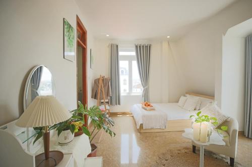 a bedroom with a bed and a table with a lamp at Huong Anh DaLat Palace in Da Lat