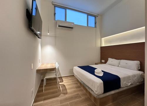 a bedroom with a bed and a television and a stool at Hotel Kapu in Puebla