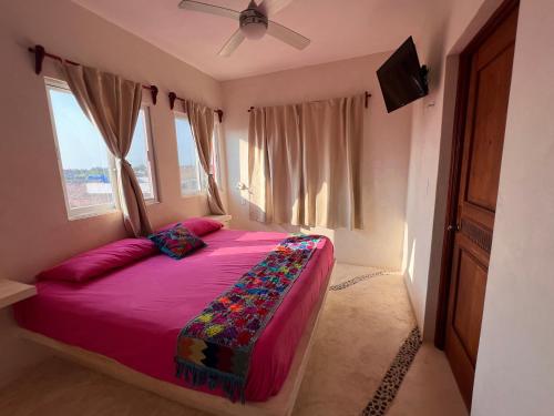 ein Schlafzimmer mit einem rosa Bett und einem Deckenventilator in der Unterkunft El CORAZÓN MEXICAN0 in Holbox