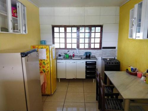 a kitchen with a refrigerator and a table in it at Chácara fortes em Pindamonhangaba in Pindamonhangaba