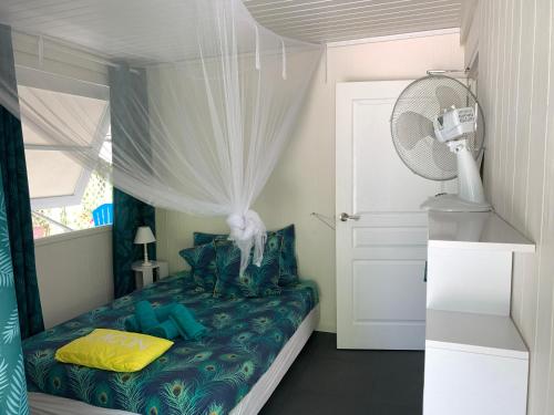 a small bedroom with a bed with a fan at LE FARE BLEU eco in Tiputa