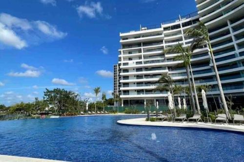 a swimming pool in front of a large building at Exclusivo y bellísimo condominio en Cabo Norte in Mérida