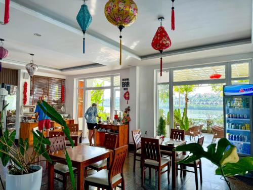 een restaurant met tafels, stoelen en ramen bij Riverside White House Boutique Hotel in Hội An