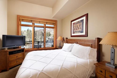 a bedroom with a bed and a tv and a window at Alpine Luxury Escape At Capitol Peak Lodge in Snowmass Village