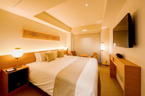 京都市にあるTHE GENERAL KYOTO 仏光寺新町の大型ベッド1台、薄型テレビが備わるホテルルームです。