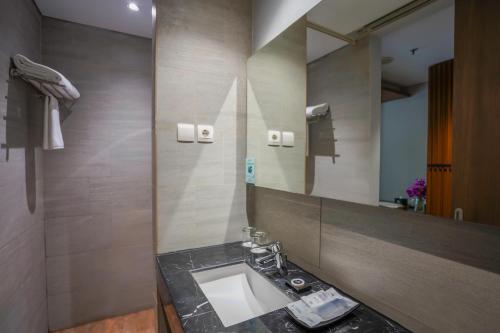 ein Bad mit einem Waschbecken und einem Spiegel in der Unterkunft BATIQA Hotel Palembang in Palembang