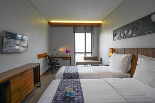 una camera d'albergo con 2 letti e una scrivania di BATIQA Hotel Palembang a Palembang