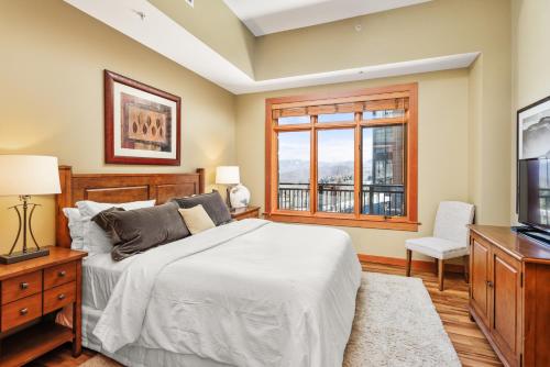 a bedroom with a bed and a tv and a window at Slope-side Oasis Premium Snowmass Mountain Condo in Snowmass Village