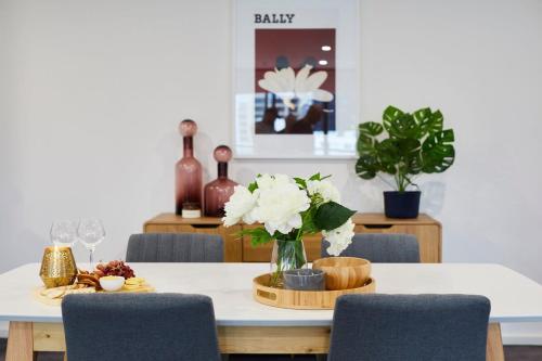 a dining room table with a vase of flowers on it at 2 Bdrm 2 Bthrm Apt With Parking in Central CBD in Melbourne