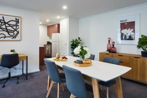 a kitchen and dining room with a white table and chairs at 2 Bdrm 2 Bthrm Apt With Parking in Central CBD in Melbourne