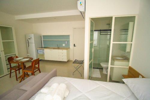 a bedroom with a bed and a table and a kitchen at Blend Coliving One - 2a in Ribeirão Preto